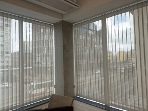 Вертикальные тканевые жалюзи в офисе в проеме окна